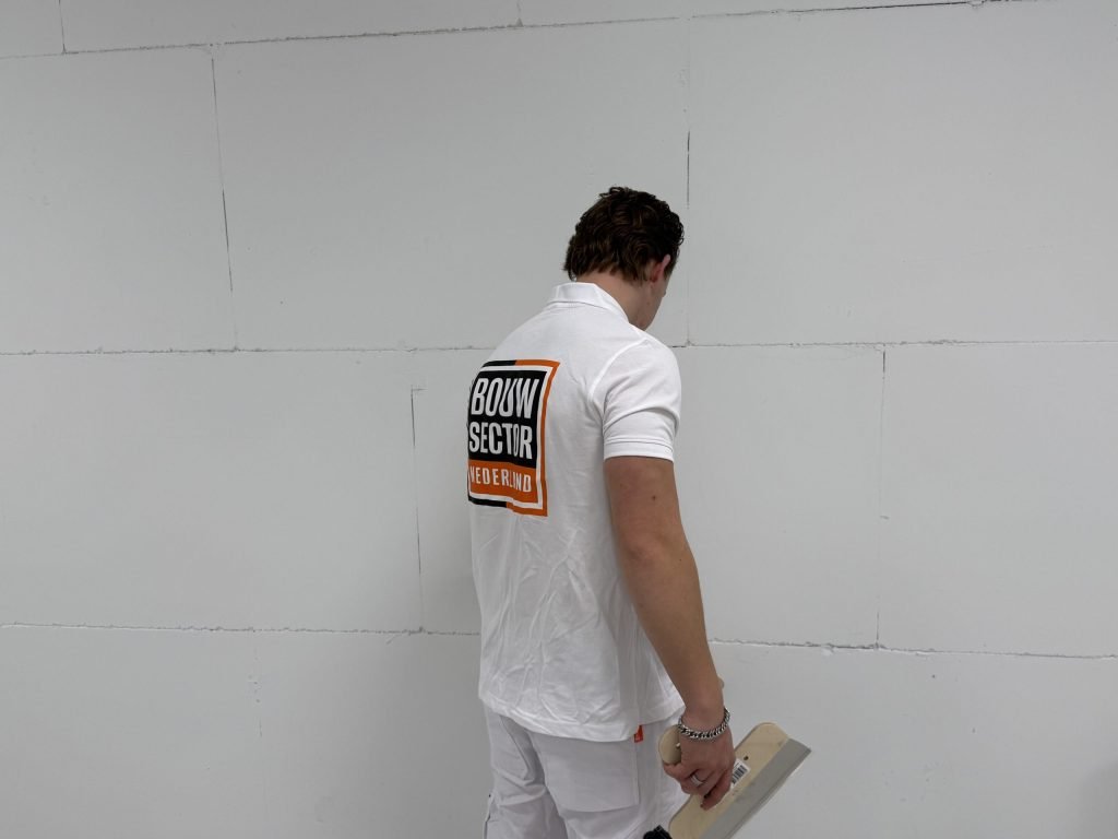 Stukadoor bekijkt de naden van een kale wand van blokken voordat hij aan het werk gaat